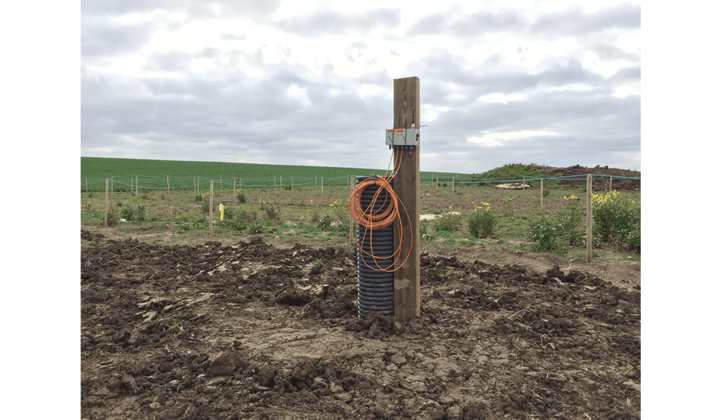 WI-SOS 480 five channel vibrating wire Node mounted on post next to borehole in a field